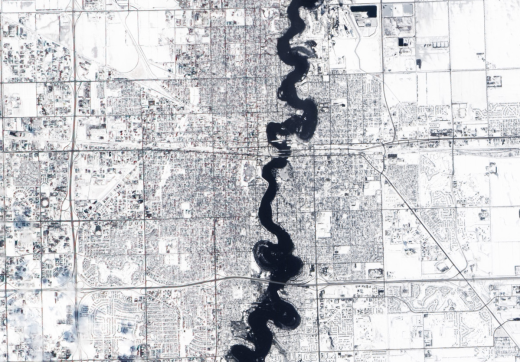Extreme events such as floods and storm surges are likely to increase with a warming climate, threatening low-lying areas in river floodplains and continental coasts. This March 28, 2009 image taken from space shows the swollen Red River snaking through the U.S. cities of Fargo, North Dakota and Moorhead, Minnesota. The river's usual S-shaped curves north and south of Interstate 94 had been swallowed in a bulge of water, and the flooding can be seen encroaching upon the tiny, neat squares that represent neighborhoods. Draining of wetlands and development along river margins contribute to the flooding risk by reducing the area over which water can spread without doing damage.

A warming world also makes heavily populated coastal areas more vulnerable to flooding: higher global temperatures produce warmer seawater, which expands and causes a rise in sea level. Approximately 400 million people live within 20 meters (0.01 miles) of sea level and 20 km (12 miles) of a coast; modest increases in sea level could displace millions of people.

Image taken by the Advanced Land Imager on NASA's EO-1 satellite on March 28, 2009.
Credit: NASA image created by Jesse Allen, using EO-1 ALI data provided courtesy of the NASA EO-1 Team. 