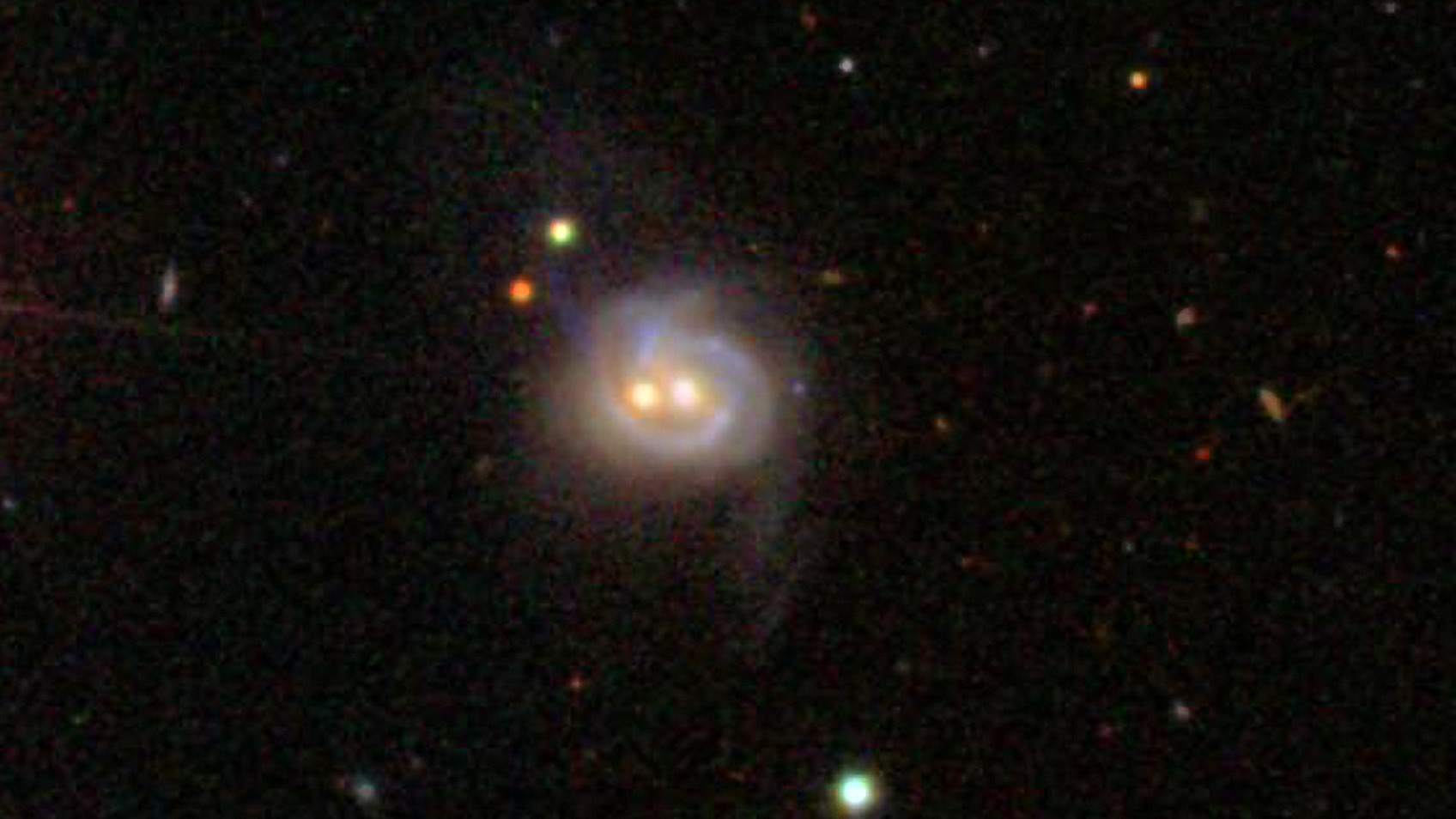 Viewed in visible light, Markarian 739 resembles a smiling face, with a pair of bright cores underscored by an arcing spiral arm. The object is really a pair of merging galaxies. Data from Swift and Chandra reveal the western core (right) to be a previously unknown AGN; past studies already had identified an AGN in the eastern core. The two supermassive black holes are separated by about 11,000 light-years. The galaxy is 425 million light-years away. Credit: SDSS