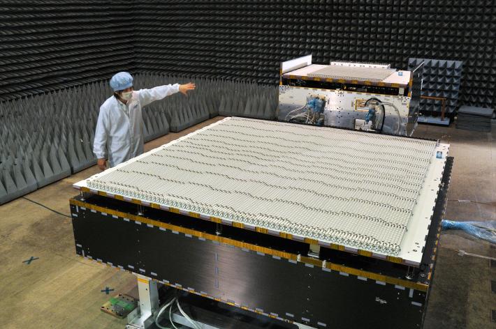 A JAXA scientist standing next to the Dual-frequency Precipitation Radar (DPR) instrument, which will be integrated onto the GPM Core Observatory satellite at Goddard Space Flight Center.The Japanese-built radar is a new instrument designed to take 3-D measurements of raindrops and snowflakes.Credit: NASA/JAXA