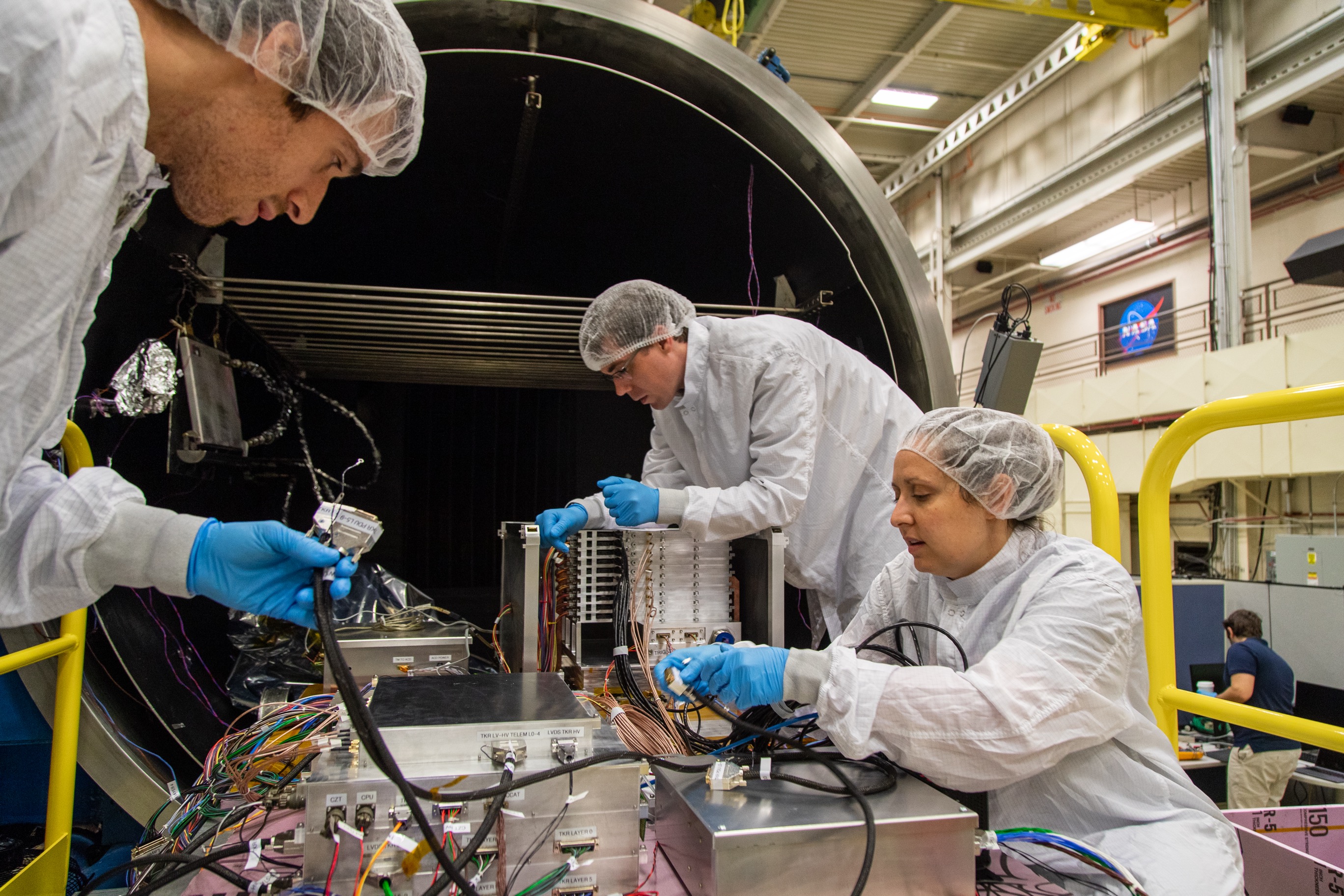 Kirschner (left), Caputo (right), and Cannady (rear) continue to harness ComPair's four main components: tracker, high-resolution low-energy calorimeter, high-energy calorimeter, and anticoincidence detector.Credit: NASA/Scott Wiessinger