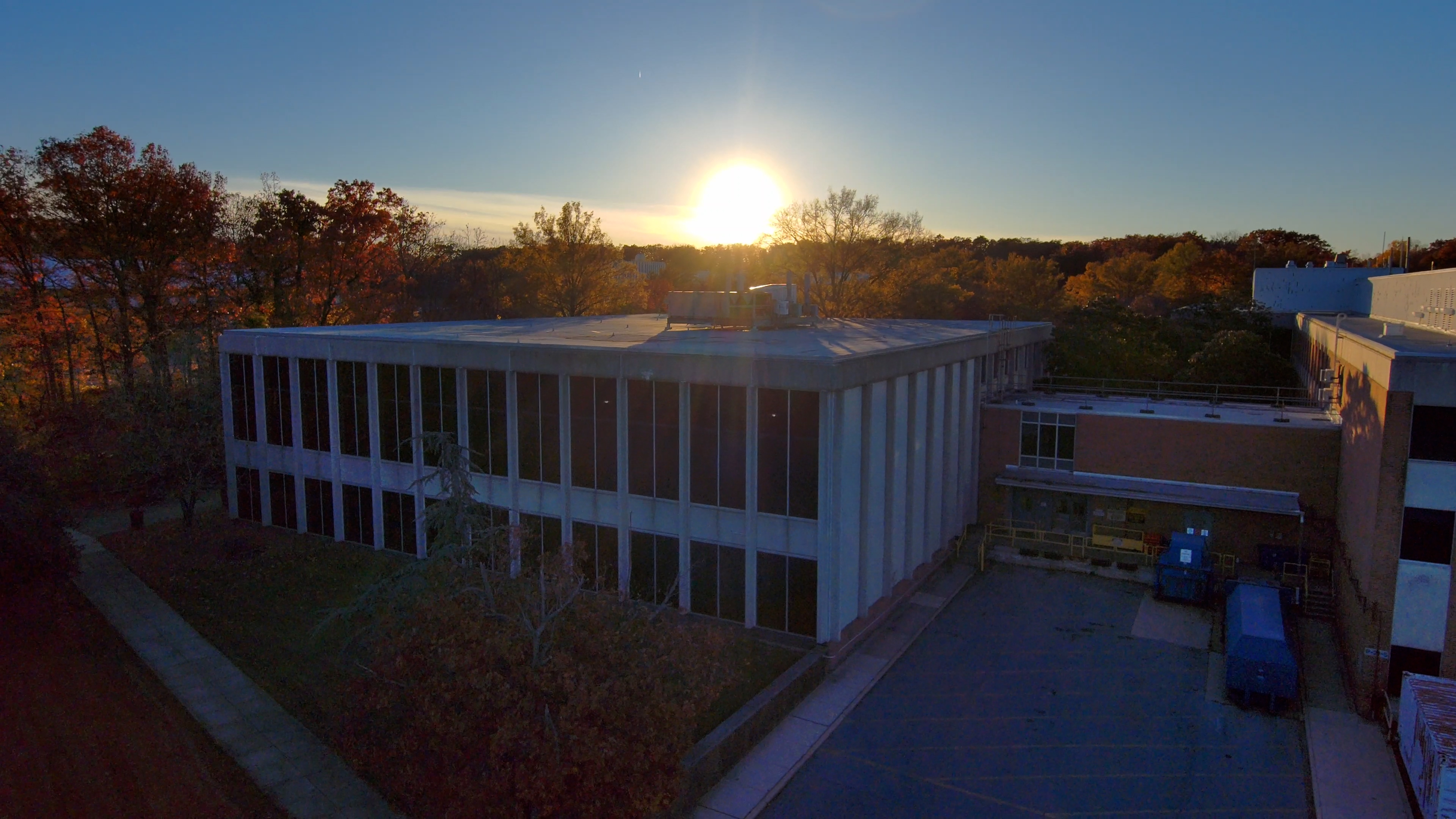 This sequence shows the northeast corner of Building 21, with the Goddard Library, near sunset and in fall colors, looking southwest. The first shot approaches the building horizontally at low altitude. The next shows a descent from moderate altitude, with Building 11 visible in the background; the following shot shows a rise to similar height and a similar descent. The next shot features a slow descent from several hundred feet, looking southwest into the sun and toward Building 11, followed by an ascent at similar pace and height. Captured Nov.14, 2023. Credit: NASA/Francis Reddy