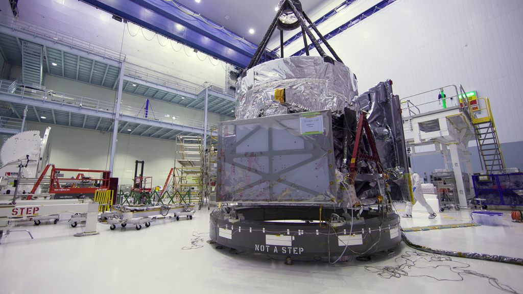 Technicians lift the Mirror assembly with the science instruments onto the Spacecraft Bus. Floor level footage.