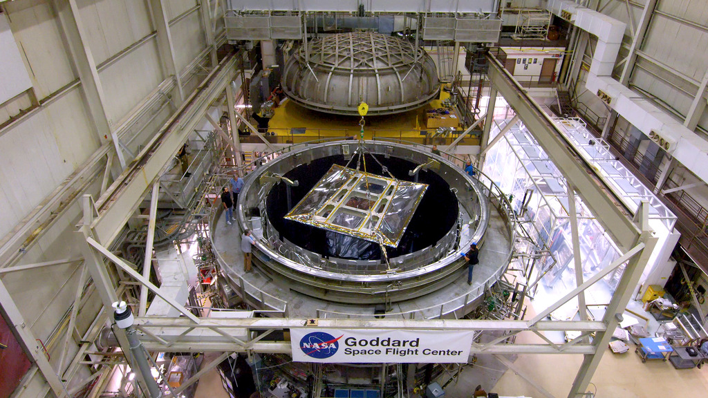 On May 1, the outer portion of NASA's Nancy Grace Roman Space Telescope, enclosed in a protective tent, emerged from testing in a vast thermal vacuum chamber and returned to NASA Goddard's biggest clean room for further work. This drone footage captures the journey.Credit: NASA/Francis Reddy0:00 A crane lifts Roman's outer layers and solar panels out of the Space Environment Simulator. 1:42 The crane moves the hardware down the facility's corridor.  2:56 Now attached to a movable platform, the assembly is pushed down the rest of the corridor and guided into Goddard's Spacecraft Systems Development and Integration Facility, a large clean room.